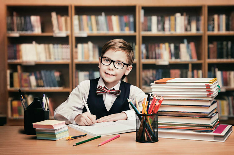 Young boy in bow tie writing.